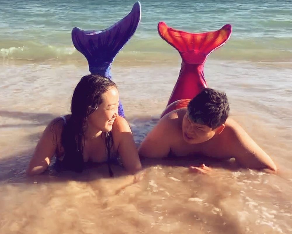 Tiff and Chris wear mermaid tails on the beach